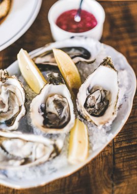 Limon ve kırmızı soğan soslu taze İrlanda istiridyeleri. Restoran masasında buzlu, seçici bir odak noktası. Deniz ürünleri, Fransız mutfağı, güzel yemek konsepti.