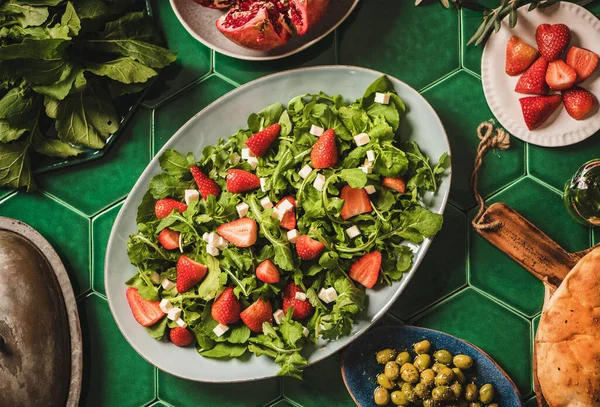 土耳其地中海餐桌设置 扁平的牛油果 奶酪和草莓沙拉 新鲜的扁平面包和橄榄覆盖在绿色的瓷砖桌子背景 顶部视图 土耳其爱琴海地区料理 — 图库照片