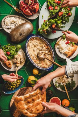 Aile, Türk usulü akşam yemeği yiyor. Yoğurt soslu kuzu eti, roka ve çilekli salata, pirinç pilavı ve düz ekmekle servis edilen bir masa. Ramazan iftar yemeği.