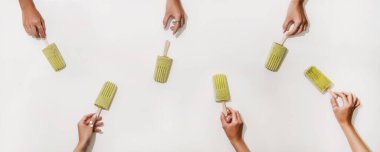 Yeşil kibrit, hindistancevizli vejetaryen dondurmalı dondurma. Bir grup kadının elleri düz beyaz masadan buzlu şekerlemeleri alıyor. Yaz sağlıklı tatlı, temiz yemek, sütsüz gıda konsepti.