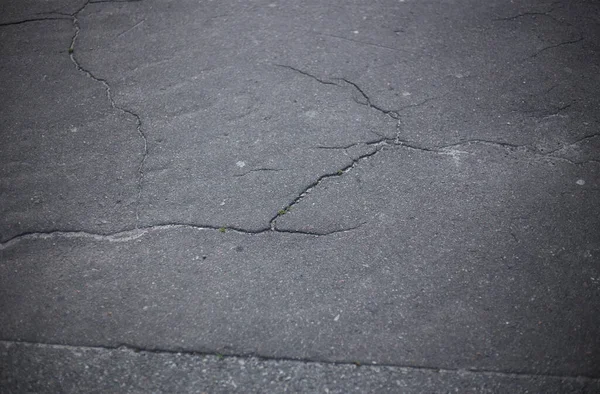 Broken asphalt and cracks on the road surface