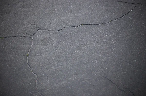 Broken asphalt and cracks on the road surface
