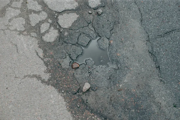 Broken asphalt and cracks on the road surface