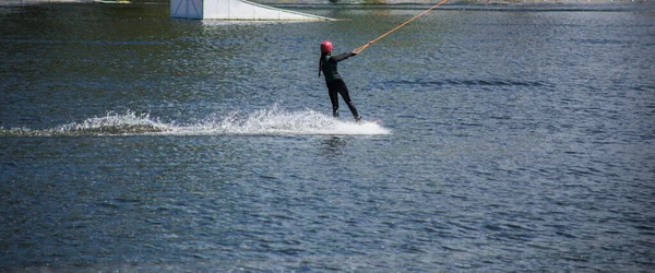 男はヘルメットとウェットスーツで夏に水の上にウェイクボードを行います — ストック写真