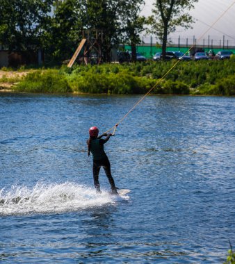 Adam yazın kask ve dalgıç kıyafetiyle suda wakeboard yapıyor..