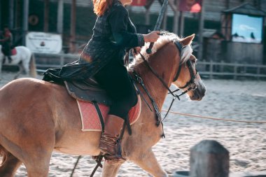 Ortaçağ kıyafetleri içinde at sırtında bir adam.