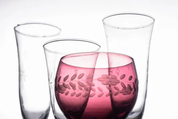 A red glass with transparent glasses around in a white background