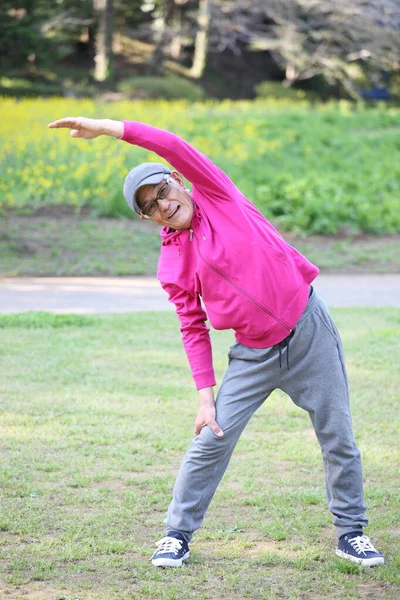 Старший Японский Мужчина Розовой Куртке Делает Стоячие Боковые Упражнения Изгиба — стоковое фото