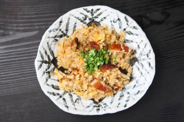 Kızarmış pirinç ve koyu arkaplanda yılan balığı.