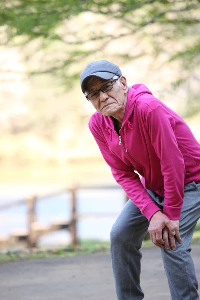 Старший Японський Чоловік Рожевому Одязі Болем Коліна Під Час Тренування — стокове фото