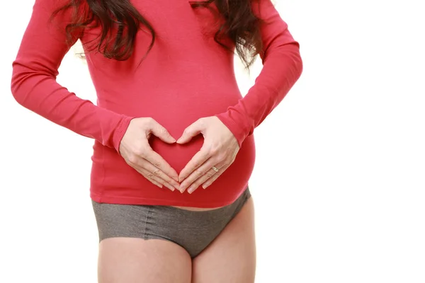 妊娠中の女性は手で心臓の形を作り — ストック写真