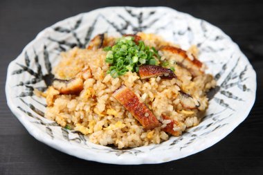 Kızarmış pirinç ve koyu arkaplanda yılan balığı.