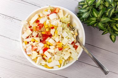 Yeşil sulu lezzetli doğal salata bir kase. Doğru beslenme ve organik vejetaryen gıda. Lahana, mısır, domates, beyaz peynir ve zeytinyağı. Açık arka plan ve yeşil yapraklar.