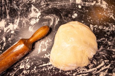 Beyaz un serpilir masaya yumuşak ve gür maya hamur. Şekerleme ve fırın. Ev yemekleri. Siyah marmor arka plan, yumuşak ışık