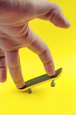 Adam Sarı zemin üzerine Mini kaykay oyuncakla oynamak