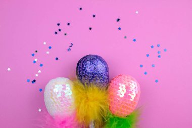 Tüylü pembe bir arka plan üzerinde renkli pullu Paskalya yumurtaları