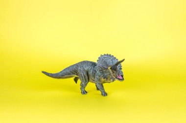 Dinozor plastik oyuncak sarı arka planda.