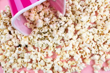 Pembe bir arka plan üzerinde pembe çizgili Kova patlamış mısır