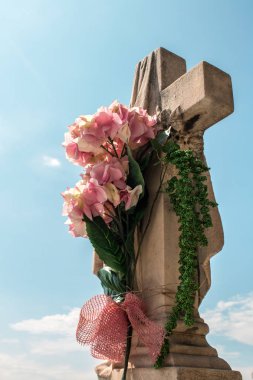 Mezarlıktaki çiçeklerle birlikte Stone Cross 'un yakın plan fotoğrafı.