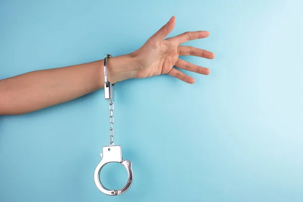 Tiro Recortado Mão Feminina Com Algemas Fundo Azul — Fotografia de Stock