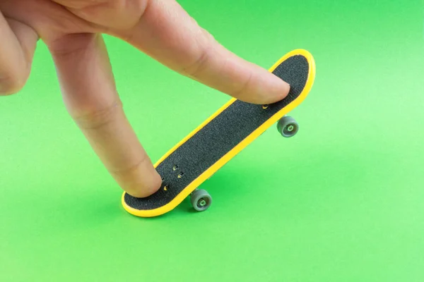 Man Spelen Met Mini Skateboard Speelgoed Groene Achtergrond — Stockfoto