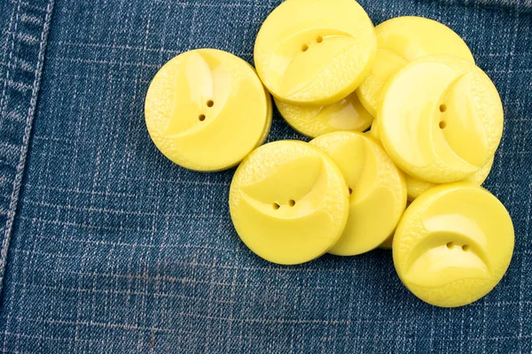 round yellow buttons on jeans background