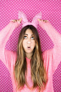 Tavşan kulaklı güzel bir kadının portresi pembemsi arka planda buruşuyor.