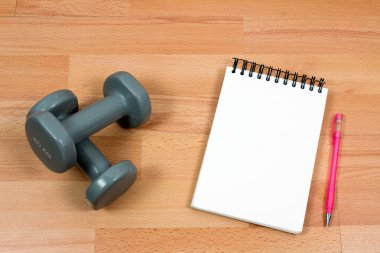 ahşap arka planda halter, kalem ve boş not defteri
