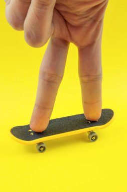 Adam Sarı zemin üzerine Mini kaykay oyuncakla oynamak