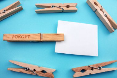 Unut işareti ve mavi arka plan üzerinde boş oyun kağıdı ile ahşap clothespins dönüştürün