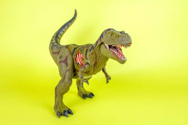 Dinozor plastik oyuncak sarı arka planda.