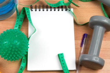 spor ekipmanları, ölçüm bandı ve ahşap arka plan üzerinde boş not defteri