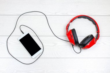 ahşap masa üzerinde akıllı telefon ve kulaklık üstten görünüm