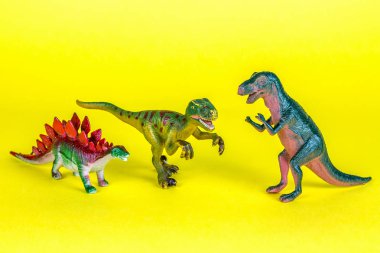 Dinozor plastik oyuncak sarı arka planda.