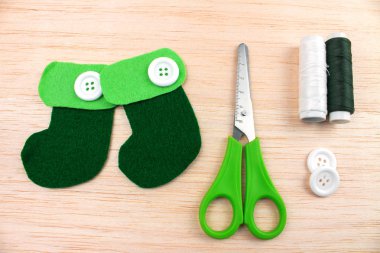 close-up shot of decorative green boots with sewing supplies on wooden table