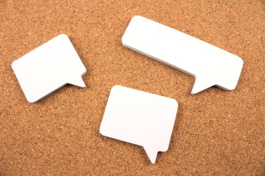 close-up shot of blank paper speech bubbles on cork background