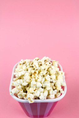 Pembe bir arka plan üzerinde pembe çizgili Kova patlamış mısır