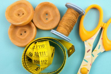 mavi zemin üzerine sarı plastik düğmeleri, konu, makas ve ölçüm bandı Üstten Görünüm