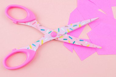 pembe Pembe bir arka plan üzerinde kağıt parçasının makasla