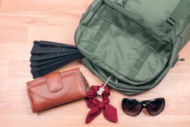 Ahşap yüzey üzerinde şık aksesuarlarla dolu sırt çantasının yakın plan fotoğrafı.