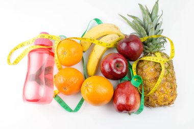 beyaz izole spor şişesinde ölçüm bantları ve su ile taze meyve 