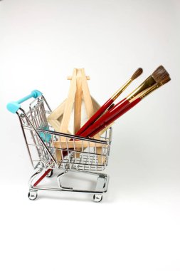Beyaz yüzeydeki boya malzemeleriyle alışveriş arabasının yakın çekim görüntüsü.