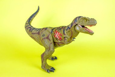 Dinozor plastik oyuncak sarı arka planda.