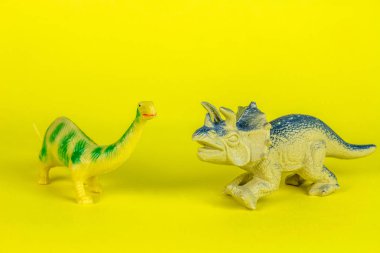 Dinozor plastik oyuncak sarı arka planda.