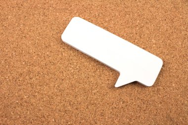 close-up shot of blank paper speech bubble on cork background
