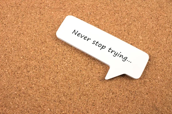 close-up shot of never stop trying phrase note on cork board surface