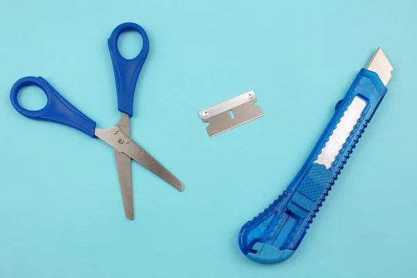 Blue Plastic Cutter, blade and scissors on Paper background