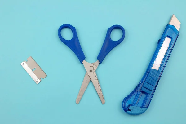 Blue Plastic Cutter, blade and scissors on Paper background