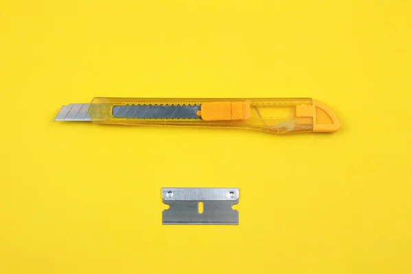 Yellow Plastic Cutter and blade on Paper background