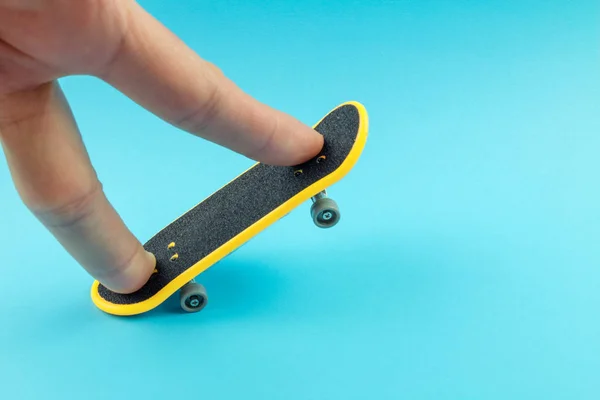 Man Spelen Met Mini Skateboard Speelgoed Blauwe Achtergrond — Stockfoto